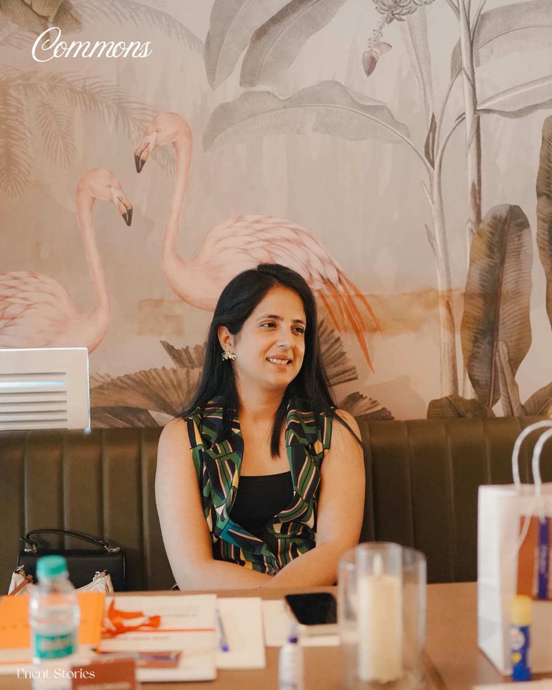 A member listening at a Commons gathering, a painted flamingo mural behind her.